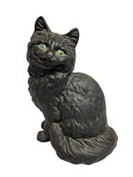 Front view of vintage cast iron black cat doorstop showing green eyes and detailed fur texture.