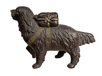 Side view of vintage cast iron dog bank showing the textured fur and pack on its back with rope detail.