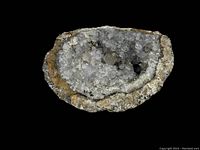 White crystal geode with white and gray crystalline interior, displayed against black background for contrast.