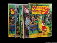Four Wizard of Oz pop-up books arranged side by side showing their colorful front covers and the box cover.