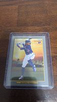 Single photo of Bo Bichette rookie card in protective case on a wooden surface.