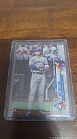 Photo showing Bo Bichette rookie card in plastic protective case resting on wooden surface.
