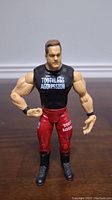 Front view of Chris Benoit action figure wearing black sleeveless shirt with Toothless Aggression text, red pants, and black boots.