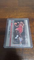 Front of LeBron James rookie card in semi-rigid plastic holder on wood surface