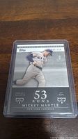 Front view of the Mickey Mantle baseball card numbered 003/150 in protective case.
