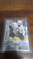 Front of Sidney Crosby short print hockey card numbered 336/899 showing Sidney Crosby in Penguins uniform skating with puck.
