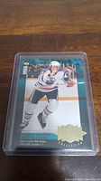 Photo of the Wayne Gretzky hockey card in plastic protective sleeve on wooden surface.