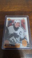 Photo of Wayne Gretzky Upper Deck hockey card in protective case showing player in white jersey with captain's 'C' and gold foil logo
