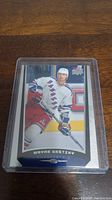 Photo of Wayne Gretzky hockey trading card in protective plastic sleeve showing him in New York Rangers uniform.