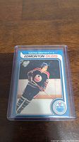 Photo of Wayne Gretzky Edmonton Oilers rookie reprint hockey card in a plastic protective case on a wood surface.