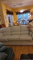 Full frontal view of the cream leather sofa in a living room setting showing the three-seat cushions and armrests.