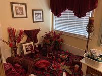 Overview photo showing red and burgundy candles, candle holders, faux floral arrangements, framed art prints, chargers, and some fabric.
