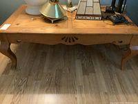 Front and top view of wooden Ponce coffee table with light scratches, Queen Anne style legs with cut out details.