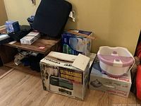 Photo showing boxed Toshiba ultrasonic humidifier, Vicks, Kaz humidifiers, Conair foot bath with massage, and miscellaneous items on shelf and floor.