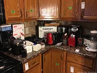 Wide shot showing multiple kitchen appliances arranged on kitchen counter including coffee makers, blender, crock pot, can opener, and other small appliances