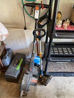 Ryobi battery weed eater (no battery), Craftsman electric edger, and two toolboxes in garage corner