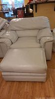 Front view of cream leather oversized chair with ottoman placed in front, showing overall condition and shape.
