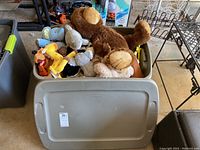 Wide view of large tote filled with various plush toys including a large brown bear, SpongeBob, Disney Simba and Pluto plush toys, and other animals.