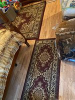 Photo showing one large rectangular rug and one runner rug on the floor with burgundy, cream and gold traditional pattern under bedroom furniture.