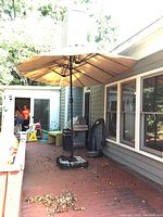 Triple umbrella installed on a deck attached to a wall, showing its size and coverage.