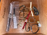 Wood box with 11 assorted watches placed inside showing variety of styles and bands.