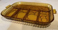 Side-angle view showcasing amber glass tray with dividers and fruit designs, and handle details.