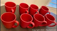 Eight red Corelle stoneware mugs shown from top angle to display quantity and inside color