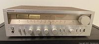 Front view of the Hitachi AM-FM Stereo Receiver SR-604 showing the brushed silver panel, control knobs, switches, tuning meter, and headphone jack.