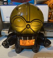 Darth Vader alarm clock with translucent amber yellow helmet lit up, showing digital time display