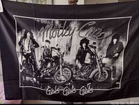 Full view of the black and white Motley Crue Girls Girls Girls nylon banner showing the band members on motorcycles and text.