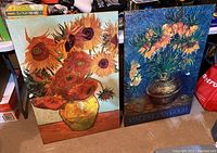 Two tall plaqued prints side by side; one of Picasso's sunflower painting and the other of Vincent Van Gogh's sunflower painting.
