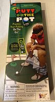 Photo of the front of the sealed box for the Putt On The Pot indoor putting practice game showing packaging design and warnings.