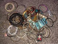 Top view of a large mixed assortment of various bracelets on a surface showing a variety of materials and colors including metal, stones, and beads.