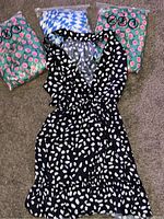 Four women's dresses in different patterns and colors, three in plastic packaging, one out in the open.