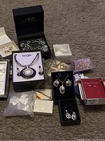 Photo showing the jewelry lot with multiple pieces in original packaging laid on carpet