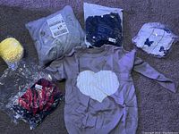 View of all items including purple heart sweater, packaged clothes and yellow yarn item.
