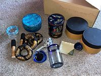 Overview of the lot including coiled woven items, decorative containers, ceramic dishes, glass jar, and other small items on carpet.