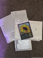 Set of eight white packaged tiles with one tile visible showing sunflower design
