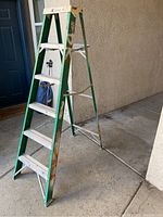 Side angled view of green and silver Davidson stepping ladder showing its condition and number of steps.
