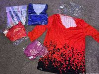 Photo shows four women's XL long sleeve shirts, three in packaging (pink/purple, blue, red) and one red shirt out of the package. All share the same floral design with scalloped neckline.
