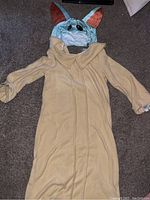 Full beige robe laid flat on carpet showing long sleeves and collar