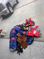 Blue and orange inflatable float tube with fins, pump, and life vests on ground near vehicle