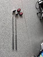 Two golf clubs with metal shafts and grips and padded club covers on a speckled floor
