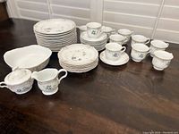 Top view photo showing the 12 dinner plates, 6 salad plates, 10 saucers, 10 cups arranged along with serving bowl and cream and sugar set.