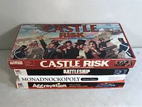 Four stacked vintage MB board games including Castle Risk on top, then Battleship, Monadnockopoly Limited Edition, Aggravation.