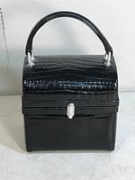 Front view of black alligator pattern handbag showing top handle and rhinestone encrusted front clasp and hardware