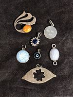 Overview of all 7 sterling silver pendants and pin on black background showing varying stones and markings including Tiffany & Co.