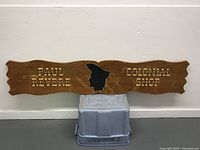 Full front view of the vintage wooden sign featuring the text and silhouette profile.