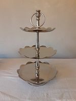 Front view of the assembled 3-tier metal server showing scalloped plates and hoop handle