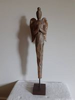 Full view of carved wooden praying angel sculpture mounted on square wooden base